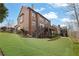 Exterior view of brick home with a spacious backyard, featuring green lawn and multi-level deck with stairs at 3060 Salisbury Ln, Cumming, GA 30041