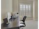 Office area showcasing a dark desk, monitor, laptop, speakers and ample natural light from shuttered windows at 3060 Salisbury Ln, Cumming, GA 30041