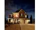 Night view of a beautiful brick home with a two-car garage and illuminated porch at 6125 Allison Rd, Cumming, GA 30040