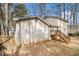 View of the home's back exterior featuring a small deck and large yard with mature trees at 1731 Fieldgreen Overlook, Stone Mountain, GA 30088