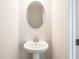 A modern pedestal sink and oval mirror are featured in this well-lit bathroom at 412 Carrera Ln, Acworth, GA 30102