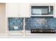 Bright kitchen featuring white cabinets, stainless steel appliances, and stylish blue backsplash at 412 Carrera Ln, Acworth, GA 30102