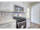 Modern kitchen features stainless steel appliances, white cabinets, light countertops, and stylish backsplash at 1230 Scenic Brook Sw Trl, Conyers, GA 30094