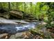 Clear creek cascading over smooth rocks, moss, and a boulder in a lush, green forest setting at 4421 Paradise Cir, Vinings, GA 30339