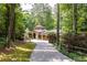 Beautiful home with stone accents, a turret, and a long brick driveway surrounded by a lush green landscape at 4421 Paradise Cir, Vinings, GA 30339