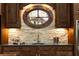 Stylish kitchenette with dark wood cabinets, stone backsplash, and an oval window feature at 4421 Paradise Cir, Vinings, GA 30339