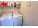 Bright laundry room features a washer, dryer, and a shelf for storage at 5175 Bridle Point Pkwy, Snellville, GA 30039