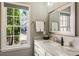 Bright bathroom featuring a marble countertop, framed mirror, and large window with a view at 741 Bentwood Trce, Alpharetta, GA 30005