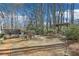 Gravel backyard with a pergola and patio seating surrounded by mature trees and foliage at 325 Upper Creek Ct, Roswell, GA 30076