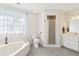 Bright bathroom featuring white cabinets, shower, soaking tub, toilet, and modern gray tile at 325 Upper Creek Ct, Roswell, GA 30076