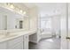 Well lit bathroom featuring white cabinets, a sink, large mirror, toilet, soaking tub and gray tile at 325 Upper Creek Ct, Roswell, GA 30076