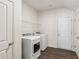 Laundry room with washer and dryer; white walls and cabinets; wood-look floors at 4645 Dandelion Way, Cumming, GA 30040