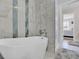Modern bathroom featuring a soaking tub, marble-look tile, and seamless glass shower, next to the Primary bedroom at 2075 Pine Tree Dr, Buford, GA 30518