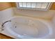 Bright bathroom featuring a large soaking tub with tile surround and a glass block window at 75 Horseshoe Dr, Covington, GA 30014