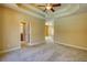 Large bedroom with a trey ceiling, carpet floors, and a doorway leading to an ensuite bathroom at 75 Horseshoe Dr, Covington, GA 30014