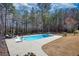 Backyard pool with lounge chairs and concrete patio is surrounded by a chain-link fence and mature trees at 75 Horseshoe Dr, Covington, GA 30014