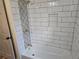 White tiled tub-shower combo with decorative tile accent and handy niche in remodeled bathroom at 938 Rebel Forest Se Dr, Atlanta, GA 30315