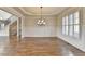 Spacious dining room featuring hardwood floors, white wainscoting, plantation shutters, and modern chandelier at 4360 Autry Way, Alpharetta, GA 30022
