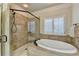 View of a soaking tub and glass enclosed shower in the main bathroom with shuttered window at 4360 Autry Way, Alpharetta, GA 30022