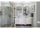 Bright bathroom featuring double sinks, framed mirrors, and a glass enclosed shower with marble tile surround at 57 Forsyth St # 13D, Atlanta, GA 30303