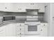 Close-up of white kitchen featuring an oven, microwave and mosaic backsplash above oven top at 747 Houston Mill Ne Rd # 1, Atlanta, GA 30329