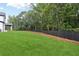 Large backyard with green grass, black fencing, and mature trees at 3165 Hall Rd, Dacula, GA 30019