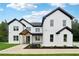 A beautiful two-story white brick home featuring black trim, black roof and lush landscaping at 3165 Hall Rd, Dacula, GA 30019