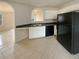 Kitchen boasts white cabinets, black appliances, and tile flooring with a view to the living room at 40 Zebulon Pl, Covington, GA 30016
