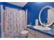 Bright blue bathroom featuring a shower with butterfly curtain, toilet, sink and a vanity with white cabinet at 4047 Round Stone Trl, Snellville, GA 30039