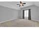 A gray bedroom featuring neutral carpet, a ceiling fan, and a window with floral curtains at 4330 Old Oak Trce, Cumming, GA 30041
