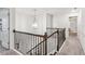 Upstairs hallway with carpet flooring, wood and iron railings, and decorative chandelier lighting at 6350 Boulder Rdg, Cumming, GA 30028