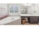 Bright bathroom featuring a large soaking tub, glass shower, dual sink vanities, and shuttered windows at 6350 Boulder Rdg, Cumming, GA 30028