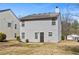 A two-story home with light gray siding, a dark brown door, and symmetrically aligned windows, seen from the backyard at 7013 Mahonia Pl, Lithonia, GA 30038