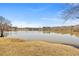 Picturesque lake view featuring a calm lake bordered by trees against a serene blue sky, captured on a sunny day at 7013 Mahonia Pl, Lithonia, GA 30038