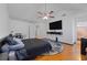 Bedroom features hardwood floors, ceiling fan and a large TV on the wall at 7013 Mahonia Pl, Lithonia, GA 30038