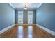 Empty room featuring hardwood floors, pale blue walls, white trim, and abundant natural light from two windows at 12 Candler Grove Dr, Decatur, GA 30030