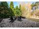 Spacious backyard patio with stone pavers, a fire pit, and ample seating surrounded by lush trees at 5230 Harris Springs Dr, Cumming, GA 30040