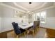 Bright dining room features a modern chandelier, tray ceiling, wainscoting, and hardwood floors at 5230 Harris Springs Dr, Cumming, GA 30040