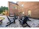 A stone patio with Adirondack chairs and a swing offers a comfortable outdoor space with a fire pit at 5230 Harris Springs Dr, Cumming, GA 30040