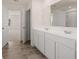 Bathroom features double sink, white cabinetry, wood look tile floor, and large mirror at 1088 Blue Juniper Cir, Loganville, GA 30052
