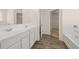 Bathroom features double sink, white cabinetry, wood look tile floor, and tub with subway tile at 1088 Blue Juniper Cir, Loganville, GA 30052