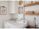 Laundry room with shelving, artwork, utility sink and modern washer and dryer at 6305 Deerwoods Trl, Alpharetta, GA 30005