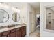 Bathroom featuring double sinks with granite counters, wood cabinets, tile floors, and a walk-in shower at 214 Avery Ne St, Marietta, GA 30060