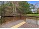 A wooden back deck with brown railings overlooking a green lawn with mature trees at 2557 Tolliver Dr, Ellenwood, GA 30294