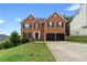 Two-story brick home featuring a two-car garage and black shutters under a clear blue sky at 2557 Tolliver Dr, Ellenwood, GA 30294