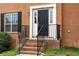 Close-up of a home's front door entrance and steps with a black handrail and brick facade at 2557 Tolliver Dr, Ellenwood, GA 30294