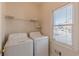 The laundry room has a washing machine and a dryer beside a window with a view of a neighboring home at 5594 Mountain View Pass, Stone Mountain, GA 30087