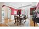Elegant dining room featuring a tray ceiling, chandelier, bay window, and red accent wall at 5952 Edenfield Nw Dr, Acworth, GA 30101