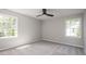 Bright bedroom featuring two large windows with backyard views, neutral carpet, and a ceiling fan at 2647 Wood Hollow Dr, Dunwoody, GA 30360