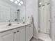 Well-lit bathroom with double sinks, a large mirror, and a separate shower area at 3280 Peace Ln, Suwanee, GA 30024